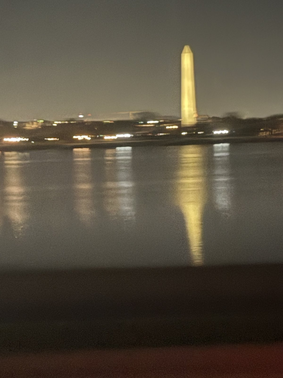 The Washington Monument lit at night, reflected in the Tidal Basin
