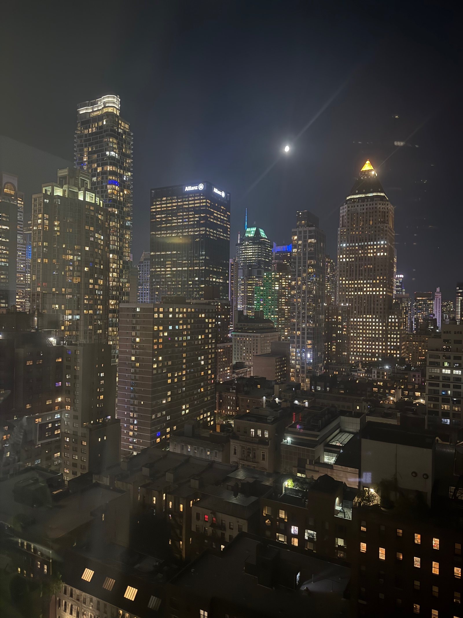 Midtown Manhattan towers lit at night under the moon